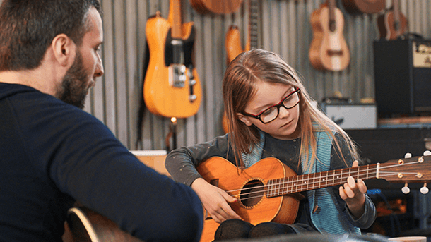 Girl learning guitar from her teacher