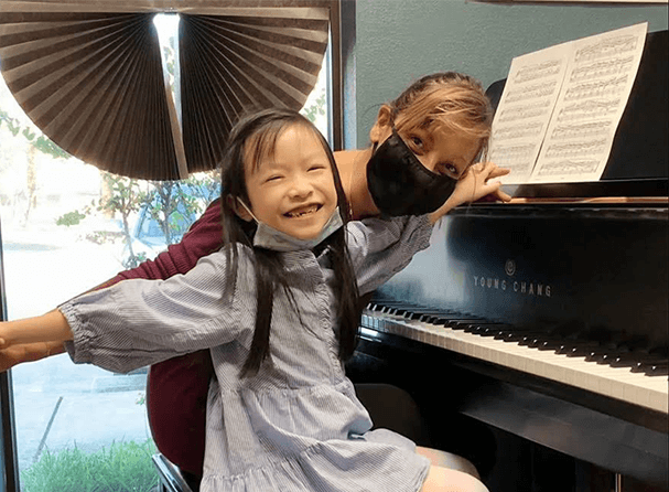 Little girl learning piano with teacher