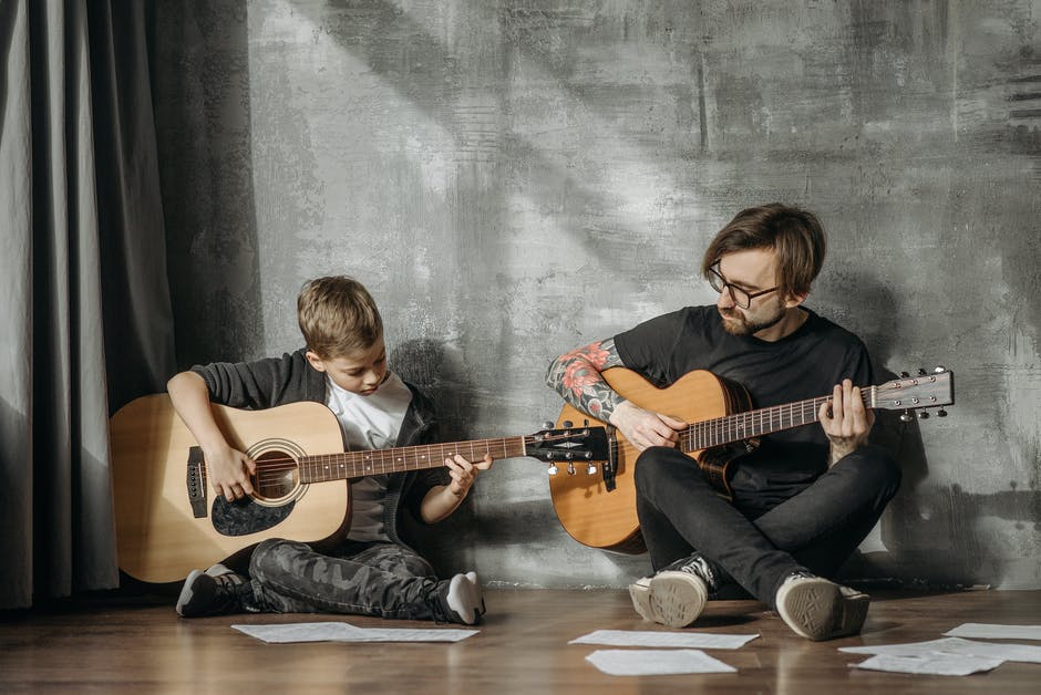 A kid and a man learning guitar